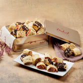 Assorted cookies in a branded tin on a wooden surface with a decorative ribbon.