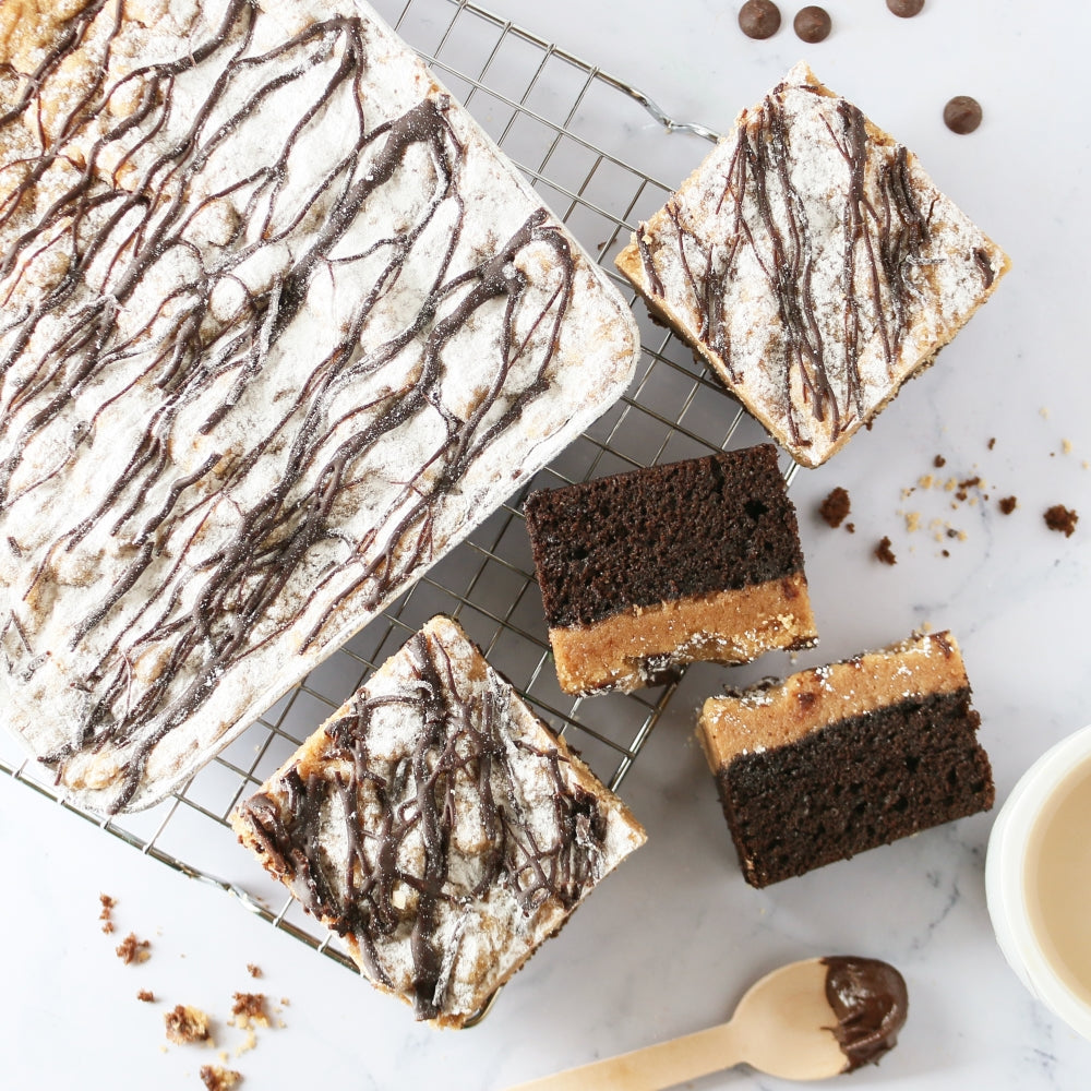 Chocolate and peanut butter bars on a cooling rack with a small bowl of coffee.