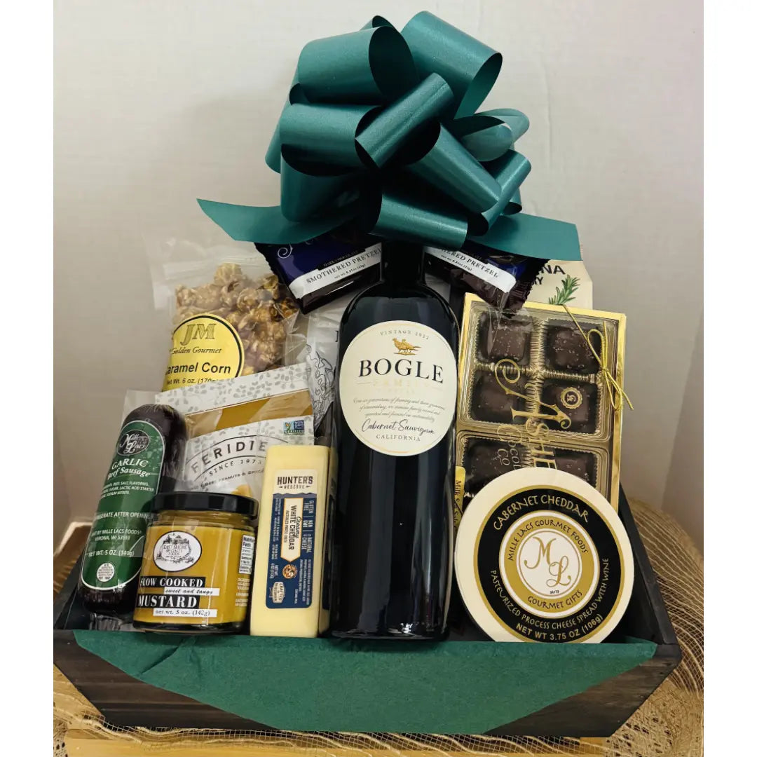 Wine and cheese gift basket with a bottle of wine, cheddar, brie and crackers on a wooden tray