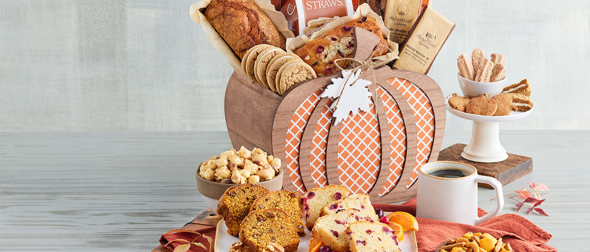 A fall gift basket with pumpkin bread, cookies, popcorn and coffee on a table