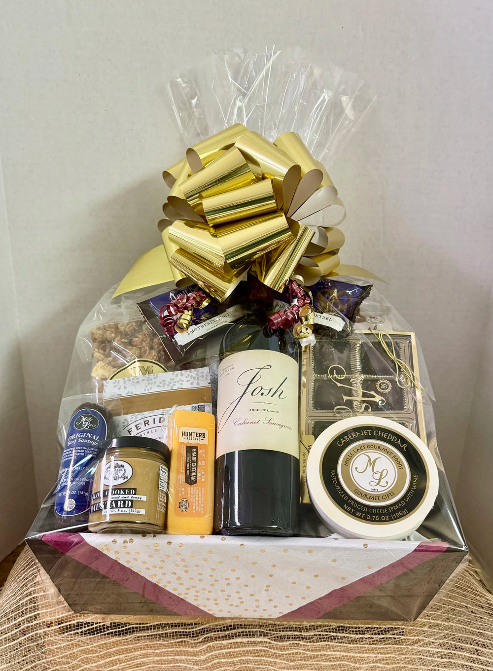 Gift basket with wine, cheese, and other snacks on a white background