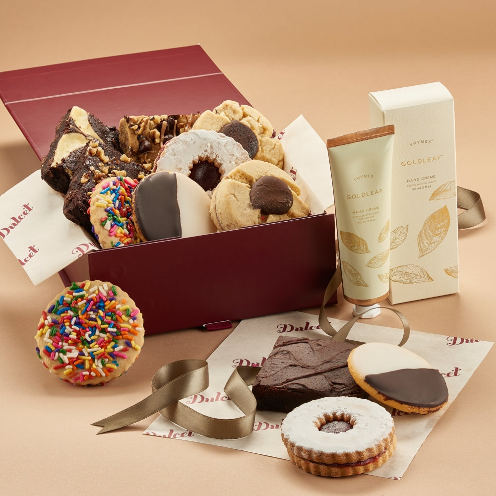Assorted cookies in a box with a tube of hand cream on a beige background