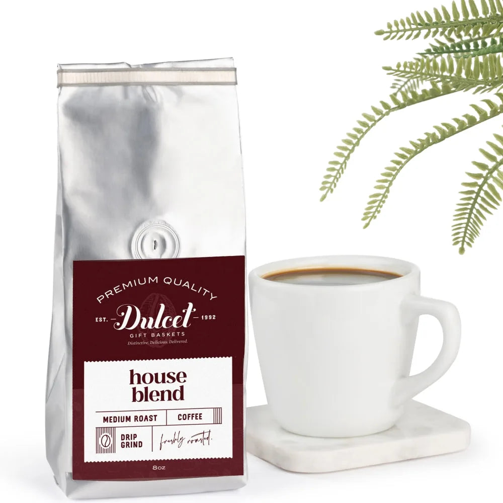 8 oz bag of Dulcet house blend medium roast drip grind coffee next to a cup of black coffee