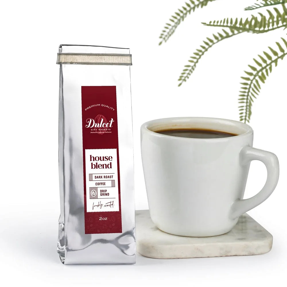 2 oz bag of Dulcet house blend dark roast drip grind coffee next to a cup of black coffee